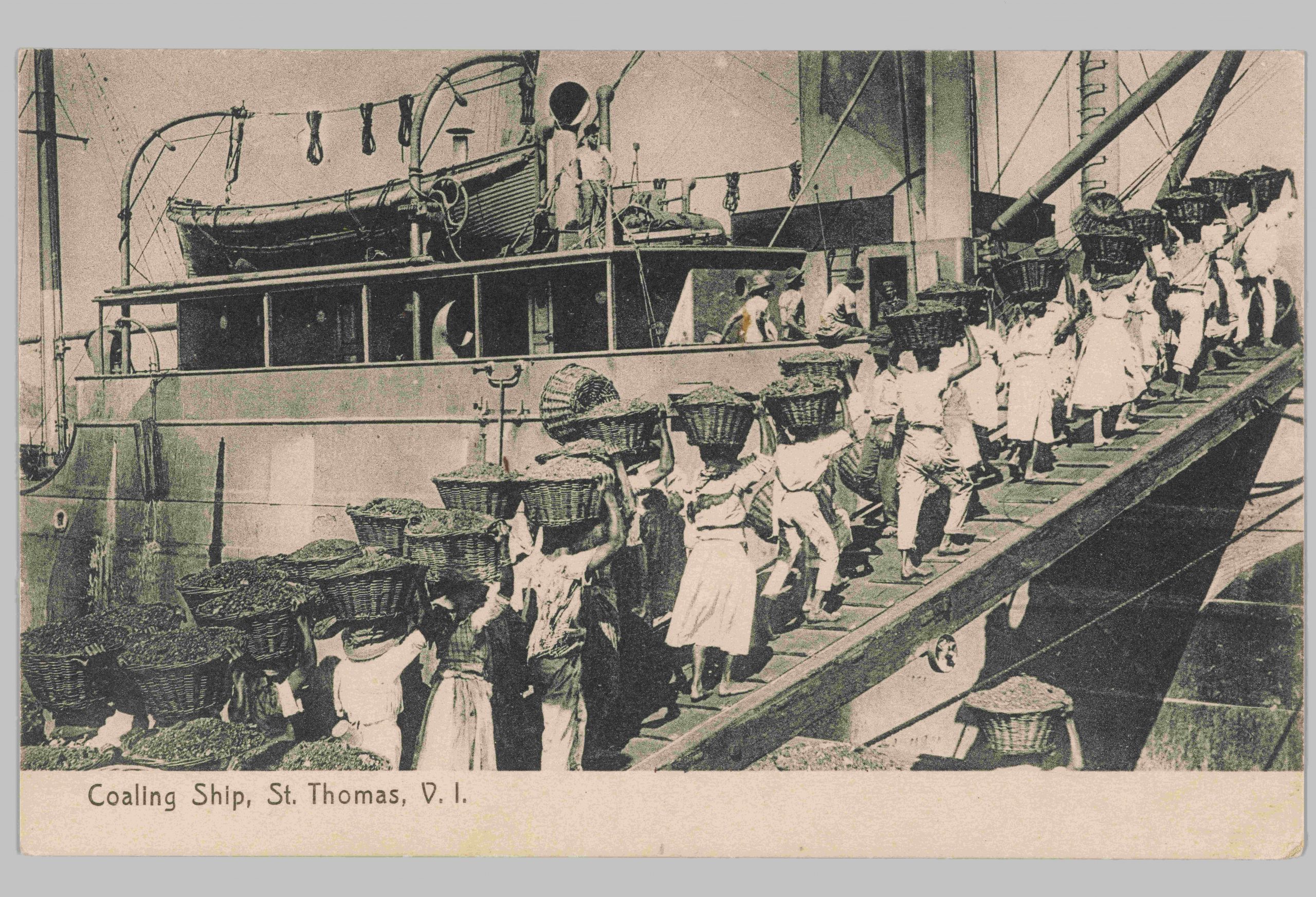 Black and white visual postcard depicts the St. Thomas coal workers boarding the ship on a wooden plank. Heavy baskets filled with coal are being balanced on their heads.